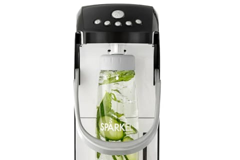 Sparkel carbonation machine in black with a bottle holding cucubmers and raspberry with bubble